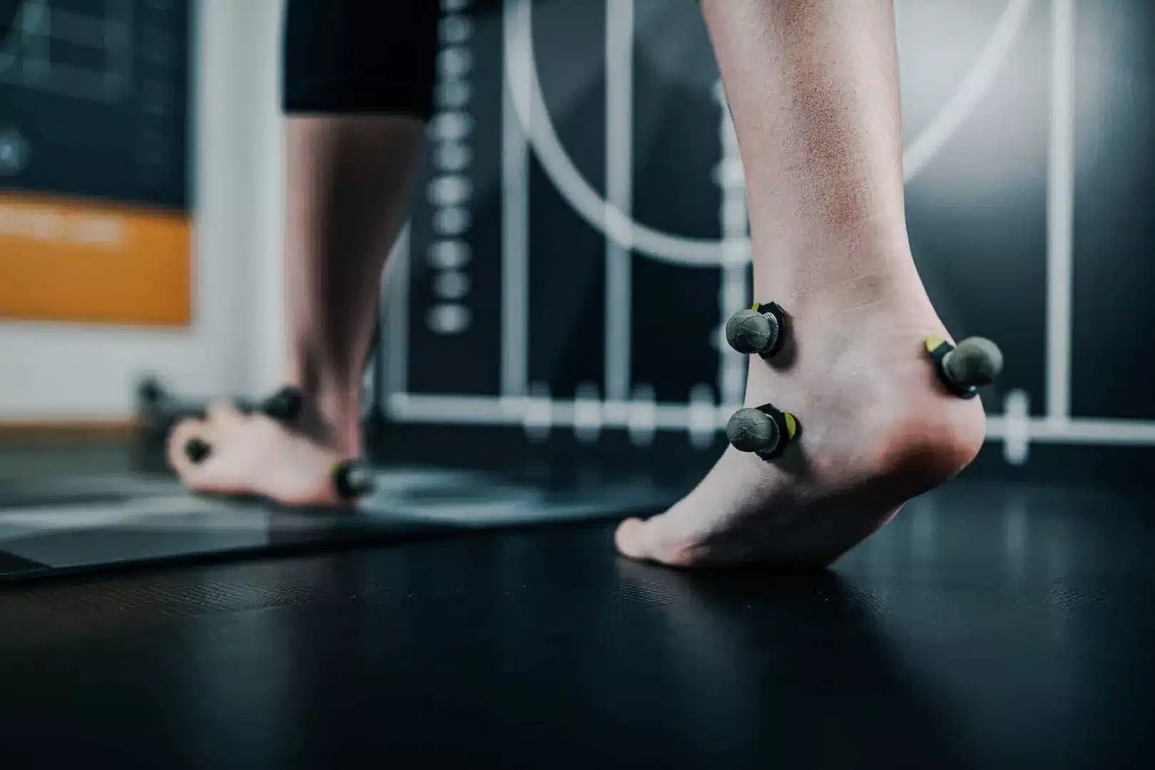 Person trägt Sensoren an den Füßen und führt Ganganalyse durch.