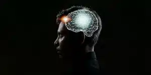 Manne vor schwarzem Hintergrund. Am Kopf ist eine Grafik eines vernetzten Gehirns abgebildet.