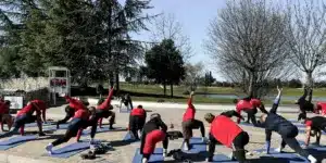 Gruppe von Männern in Sportklamotten auf Matten auf einer Terasse und machen Übungen zur Regeneration